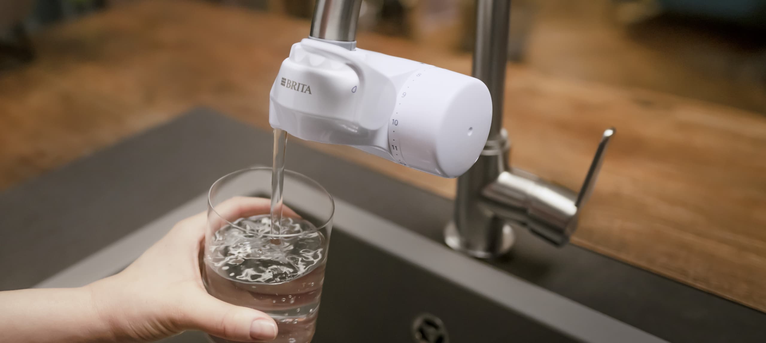 Glass filled with BRITA ON TAP Pro V-MF water filter system